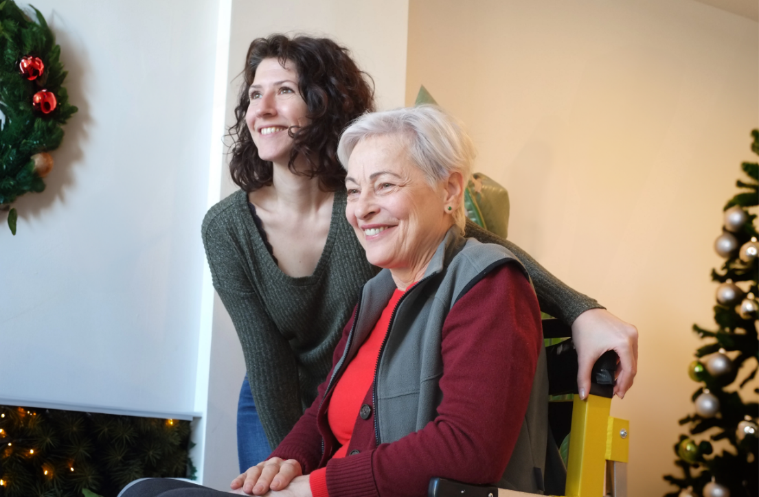 Two women smiling during the holidays while one uses a stair lift chair