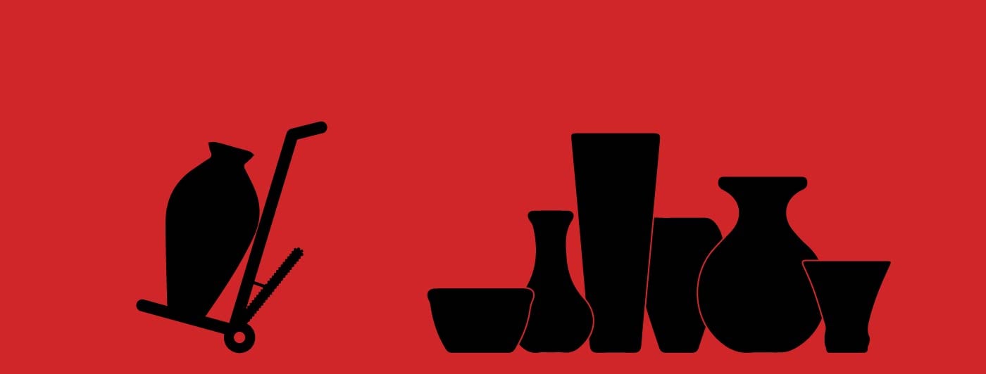 A hand truck next to vases of many shapes